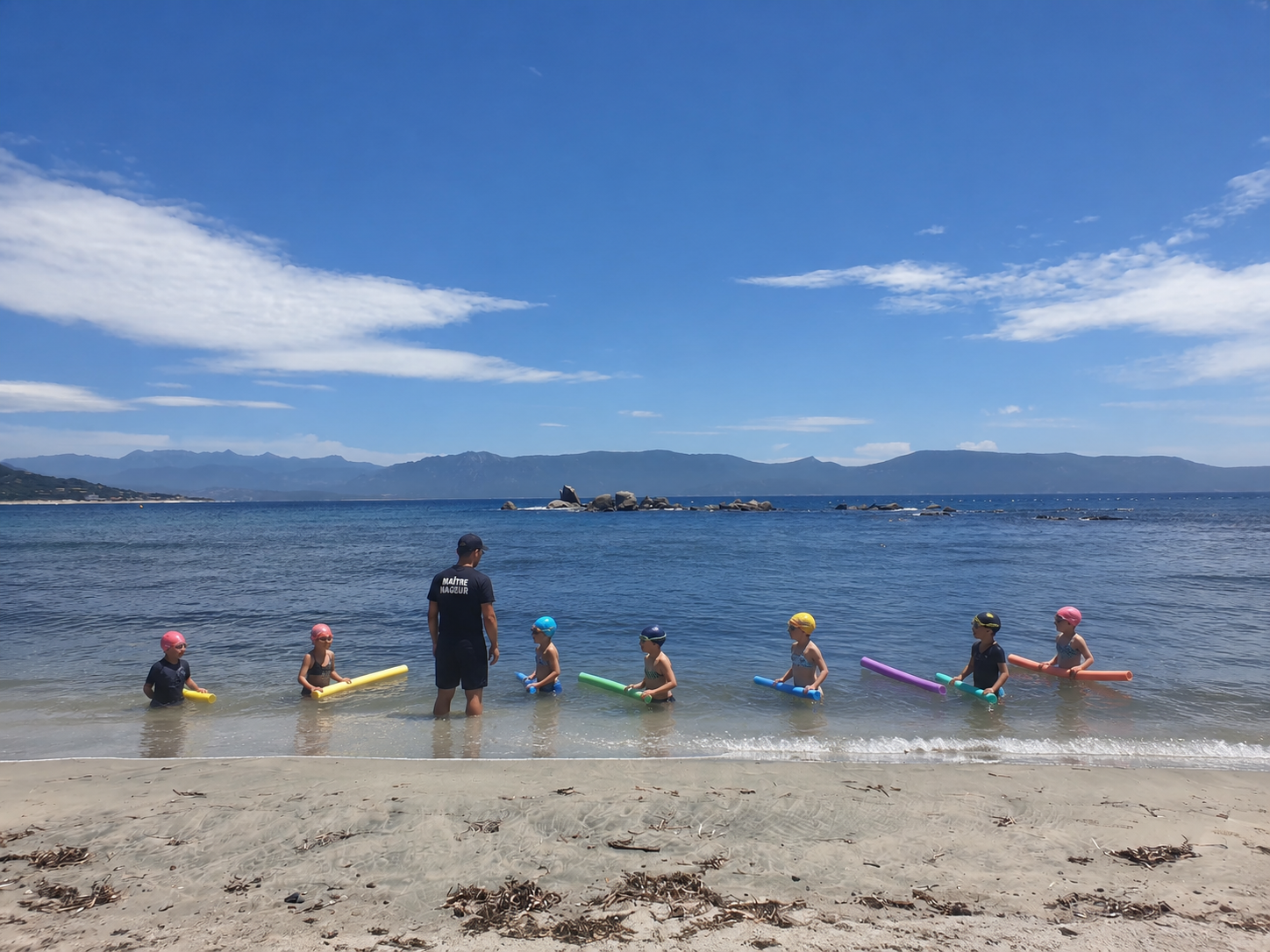 Cours collectif de natation pour enfants dispensé par un maître-nageur de l'association LESEA sur la plage à Porto Pollo.